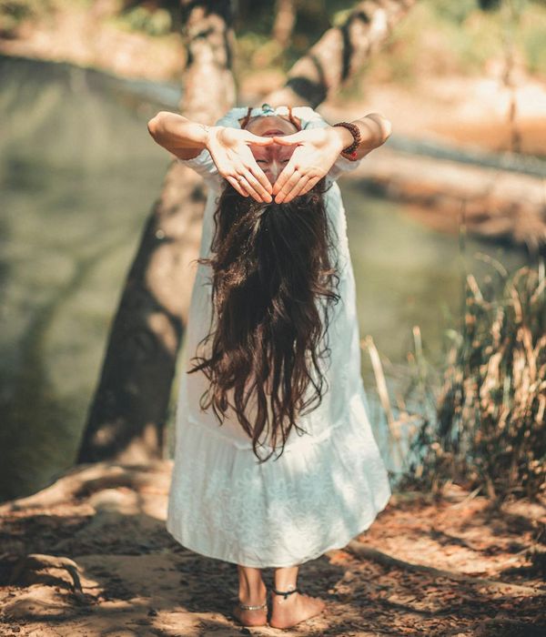 Woman performing a fluid yoga pose in a dark, serene environment.